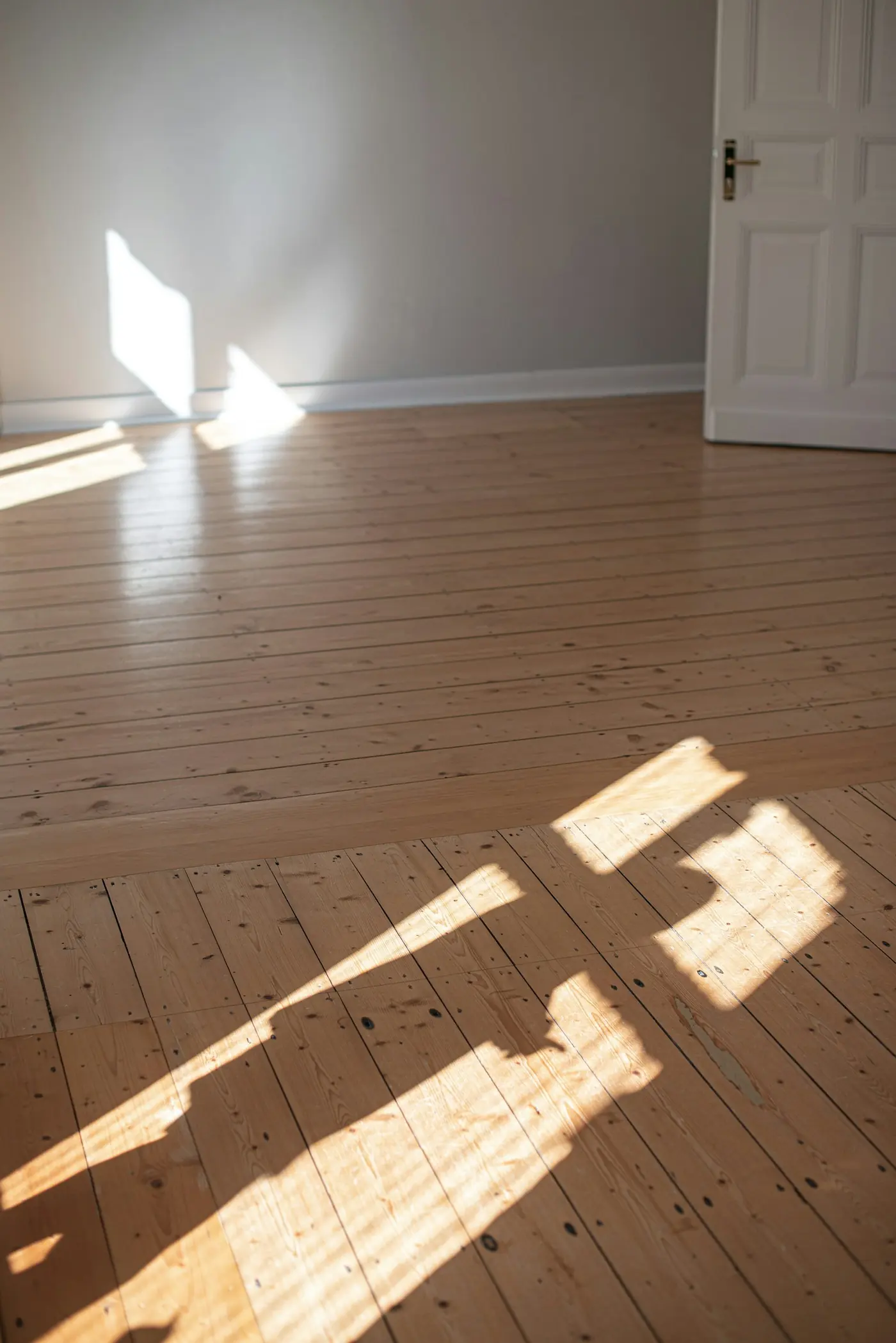 Parquet en bois clair et porte blanche dans une pièce rénovée